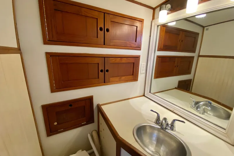 Wonder Yacht Photos Pics Compact bathroom with wooden cabinets, mirror, and stainless steel sink in a 1980 Wellington 44.