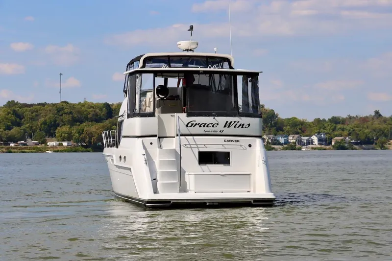 Grace Wins II Yacht Photos Pics 2001 Carver 406 Motor Yacht on a serene river, surrounded by lush greenery.