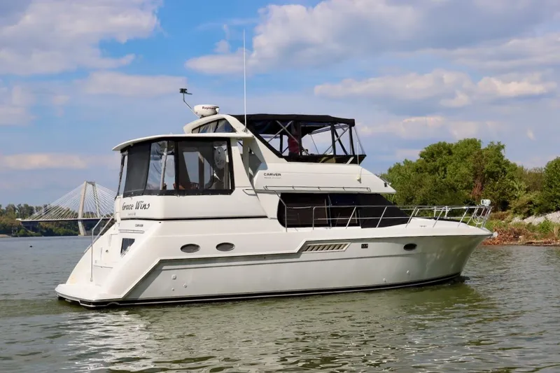 Grace Wins II Yacht Photos Pics 2001 Carver 406 Motor Yacht cruising on a river with a bridge in the background.