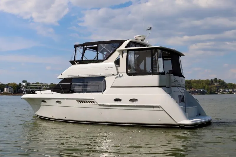 Grace Wins II Yacht Photos Pics 2001 Carver 406 Motor Yacht cruising on a calm lake under a partly cloudy sky.