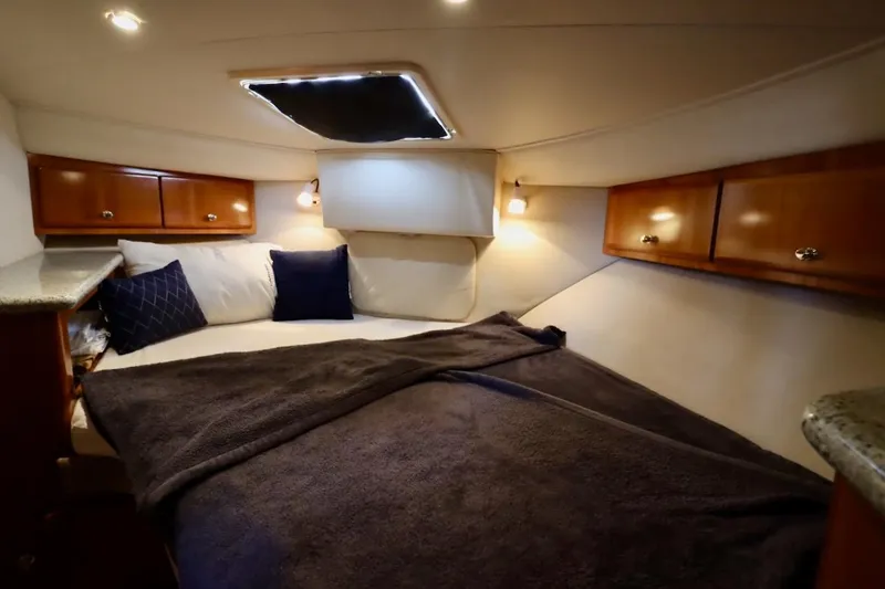Grace Wins II Yacht Photos Pics Luxurious cabin interior of 2001 Carver 406 Motor Yacht with cozy bedding and wooden cabinets.