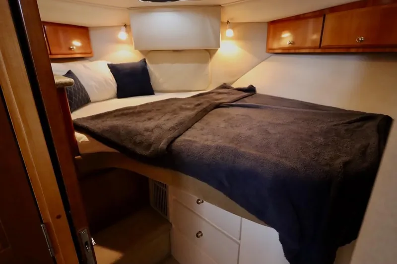 Grace Wins II Yacht Photos Pics Cozy bedroom in 2001 Carver 406 Motor Yacht with wooden cabinets and soft lighting.