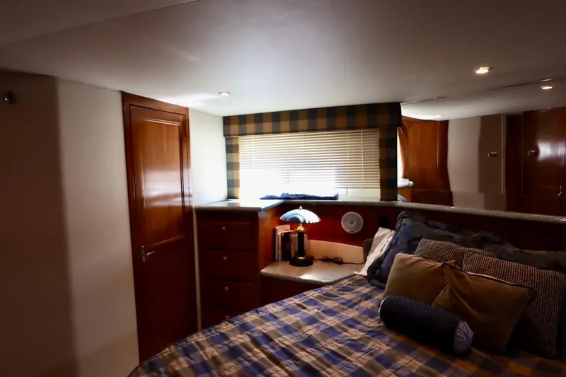 Grace Wins II Yacht Photos Pics Luxurious bedroom interior of 2001 Carver 406 Motor Yacht with plaid bedding and wooden cabinetry.