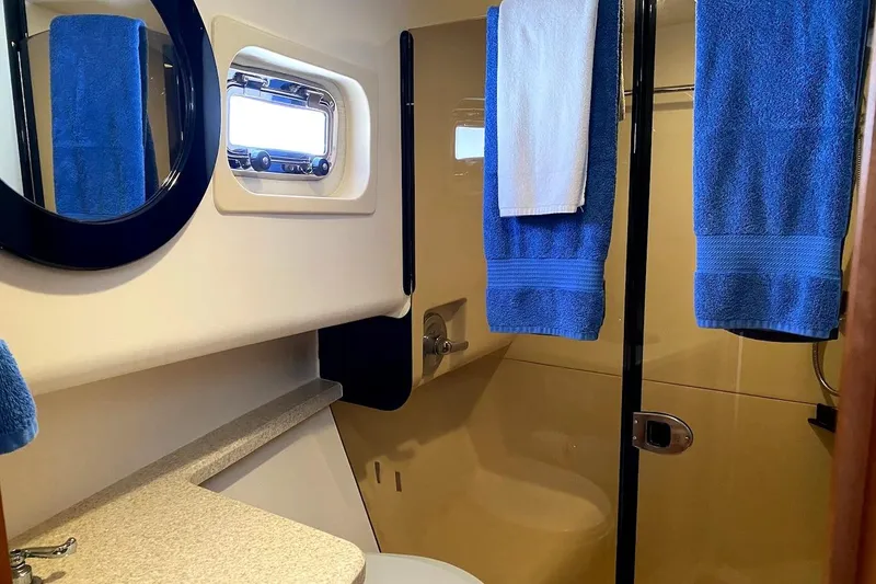 Hellion Yacht Photos Pics Bathroom interior of 2005 Mainship 34 Trawler with blue towels and porthole window.