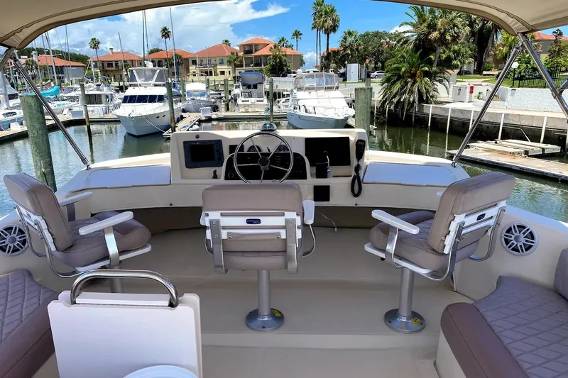 Hellion Yacht Photos Pics 2005 Mainship 34 Trawler helm with seating, docked in a marina with palm trees.