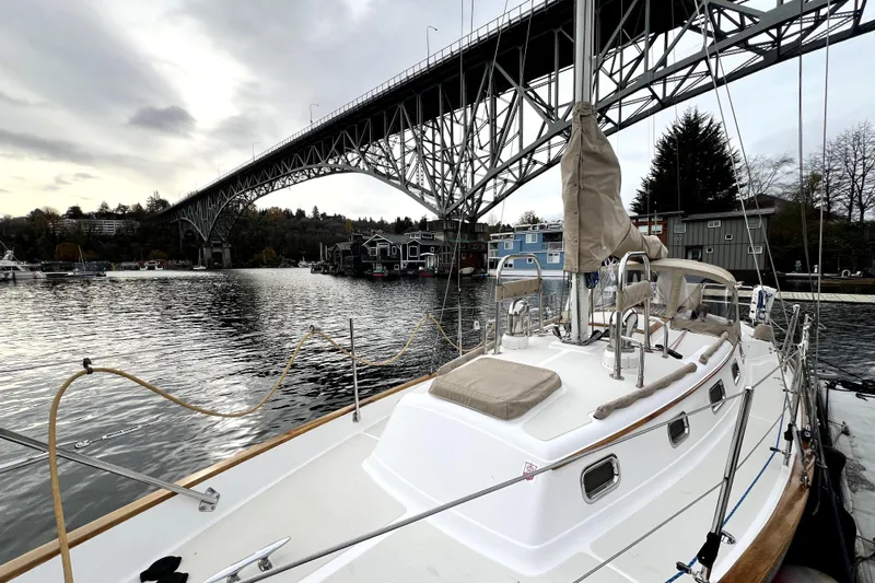  Yacht Photos Pics 2004 Pacific Seacraft 31 sailboat docked under a large bridge on a cloudy day.
