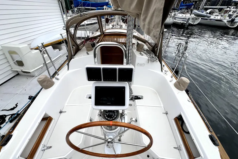  Yacht Photos Pics Cockpit of 2004 Pacific Seacraft 31 sailboat with navigation equipment and wooden steering wheel.