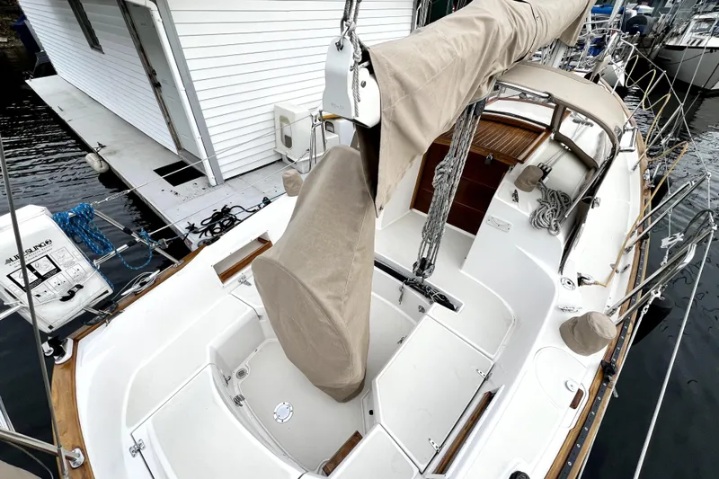  Yacht Photos Pics 2004 Pacific Seacraft 31 sailboat with covered cockpit, docked beside a white building.