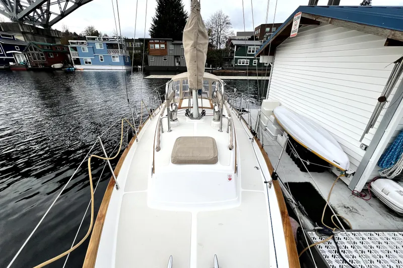  Yacht Photos Pics 2004 Pacific Seacraft 31 sailboat docked near colorful houseboats and a bridge.