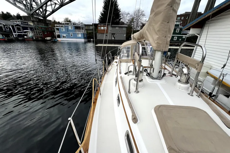  Yacht Photos Pics 2004 Pacific Seacraft 31 sailboat docked near colorful houseboats under a bridge.