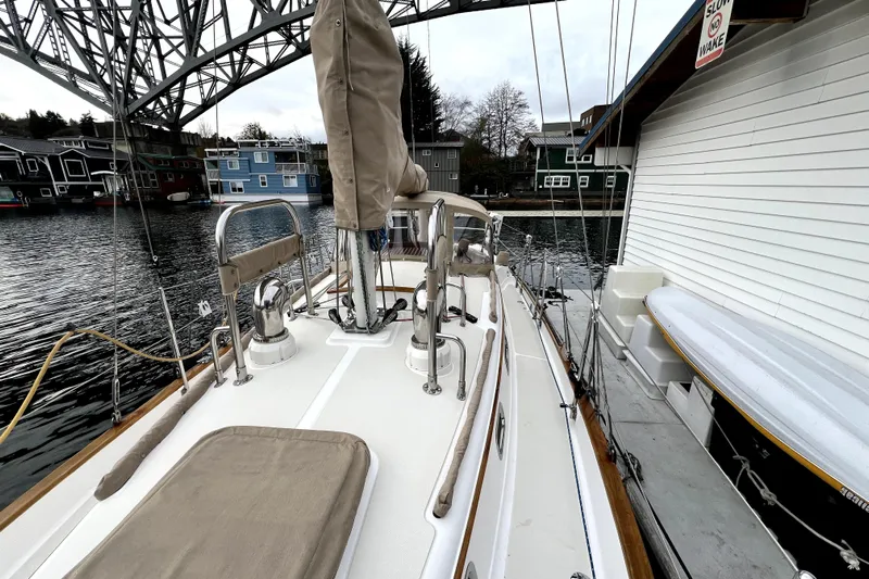  Yacht Photos Pics 2004 Pacific Seacraft 31 sailboat docked near waterfront homes under a bridge.