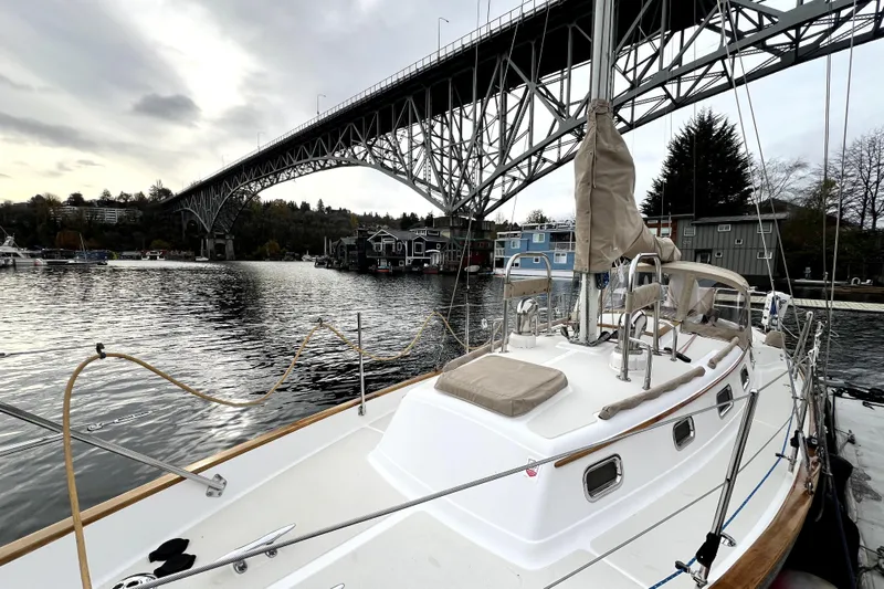  Yacht Photos Pics 2004 Pacific Seacraft 31 sailboat docked under a large bridge on a cloudy day.