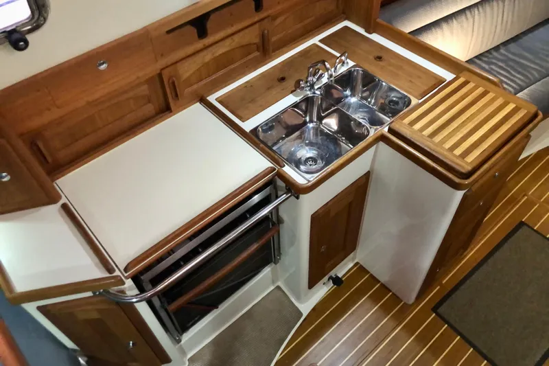 Murphy Yacht Photos Pics Interior of 2004 Pacific Seacraft 31 sailboat, featuring a compact kitchen with wooden cabinetry.