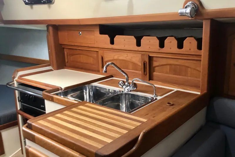 Murphy Yacht Photos Pics 2004 Pacific Seacraft 31 yacht kitchen with wooden cabinetry and stainless steel sink.