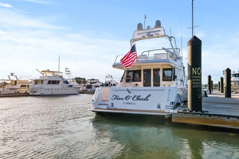 Five O' Clock Yacht Photos Pics 2000 West Bay 58 Sonship yacht docked with American flag, calm marina setting.