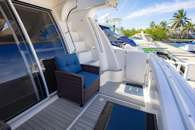 Blue Sapphire Yacht Photos Pics 2001 Silverton 410 Sport Bridge yacht deck with wicker chair, docked near palm trees.