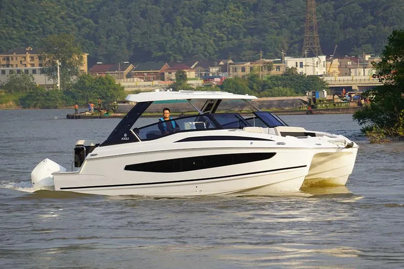  Yacht Photos Pics Manufacturer Provided Image: Aquila 32 Sport 2021 cruising on a scenic river with lush greenery.