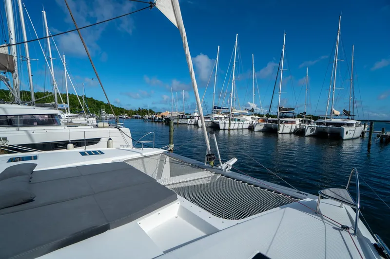 Hourglass Yacht Photos Pics 2020 Fountaine Pajot Saona 47 catamaran docked in a marina with clear blue skies.