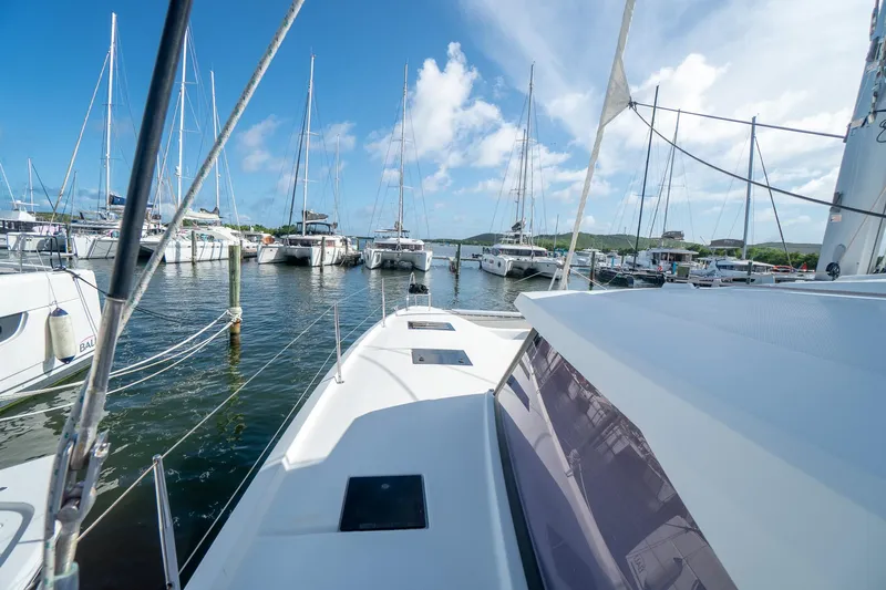 Hourglass Yacht Photos Pics 2020 Fountaine Pajot Saona 47 catamaran docked in a marina under a clear blue sky.