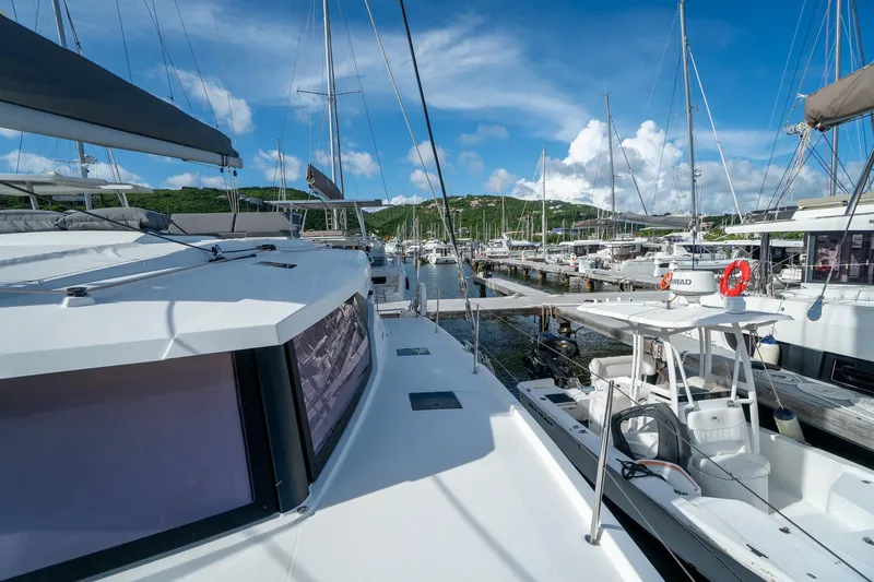 Hourglass Yacht Photos Pics 2020 Fountaine Pajot Saona 47 catamaran docked at a marina under a clear blue sky.