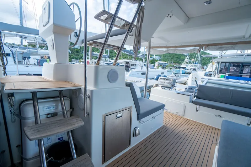 Hourglass Yacht Photos Pics Fountaine Pajot Saona 47 yacht interior, featuring seating and wooden flooring, docked at a marina.