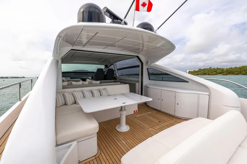Sea Suite Yacht Photos Pics Luxurious 2021 Pershing 62 yacht deck with seating, table, and Canadian flag.