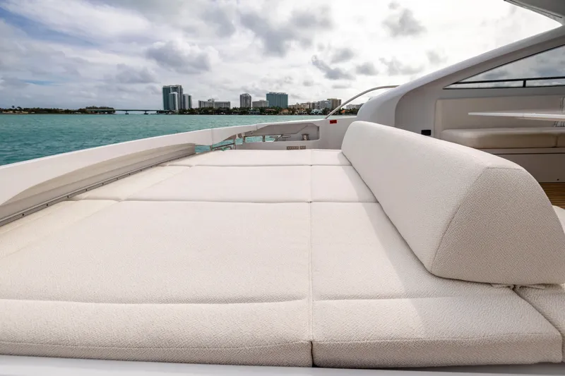 Sea Suite Yacht Photos Pics Luxurious sunbed on 2021 Pershing 62 yacht, overlooking serene ocean and city skyline.
