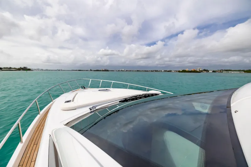 Sea Suite Yacht Photos Pics 2021 Pershing 62 yacht cruising on turquoise waters under a cloudy sky.