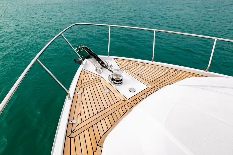 Sea Suite Yacht Photos Pics Bow of 2021 Pershing 62 yacht with teak deck on turquoise water.