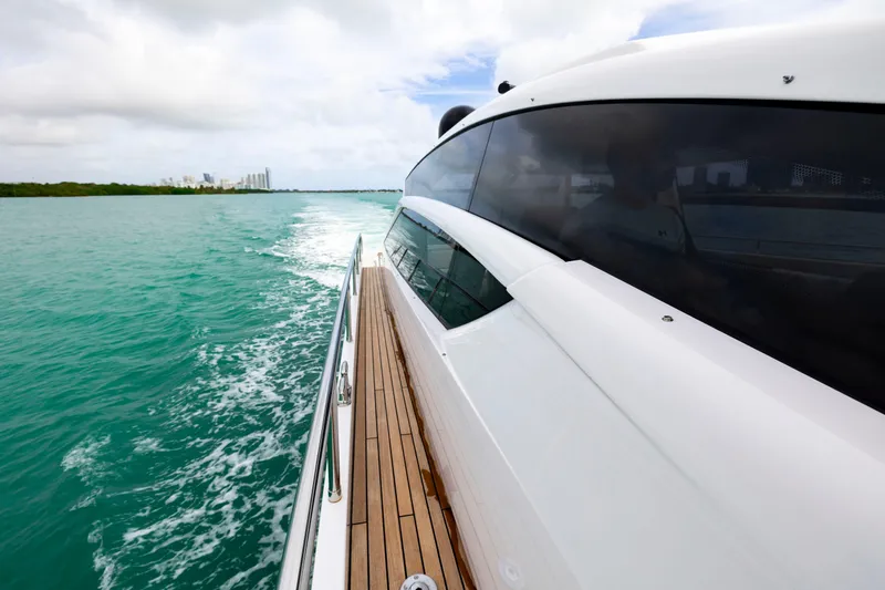 Sea Suite Yacht Photos Pics 2021 Pershing 62 yacht cruising on turquoise waters, showcasing sleek design and wooden deck.