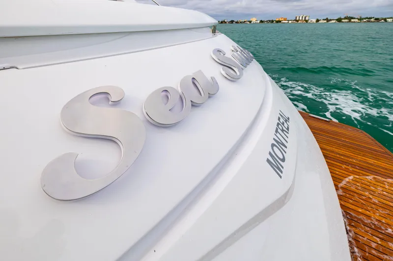 Sea Suite Yacht Photos Pics 2021 Pershing 62 yacht stern with "Sea Suite" name, wooden deck, ocean view.