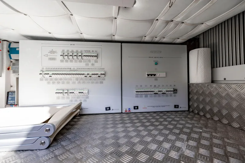 Sea Suite Yacht Photos Pics Electrical control panels inside a 2021 Pershing 62 yacht, featuring circuit breakers and metallic flooring.