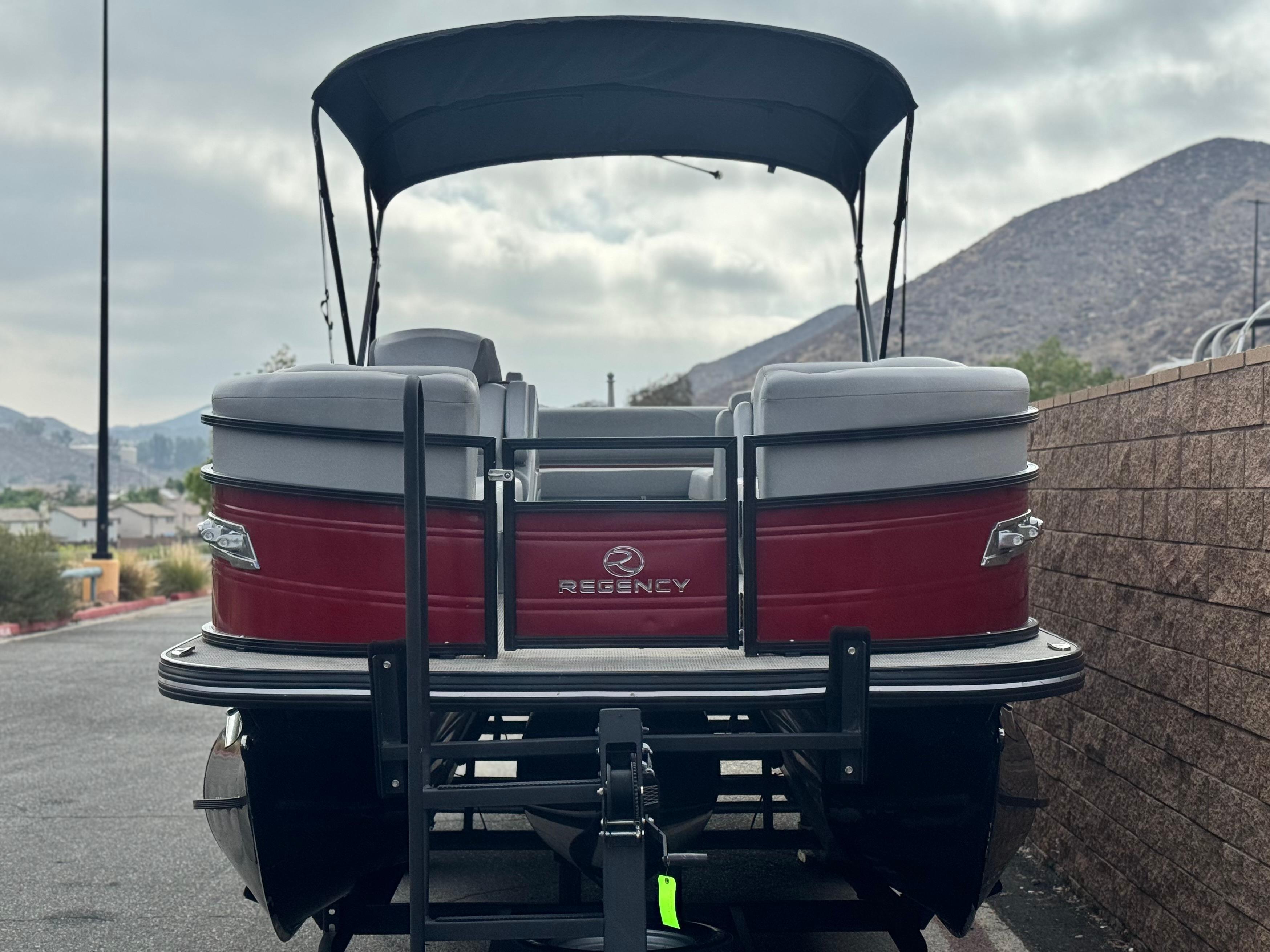 2023 Regency 250 DL3 pontoon boat with canopy, parked near mountains.