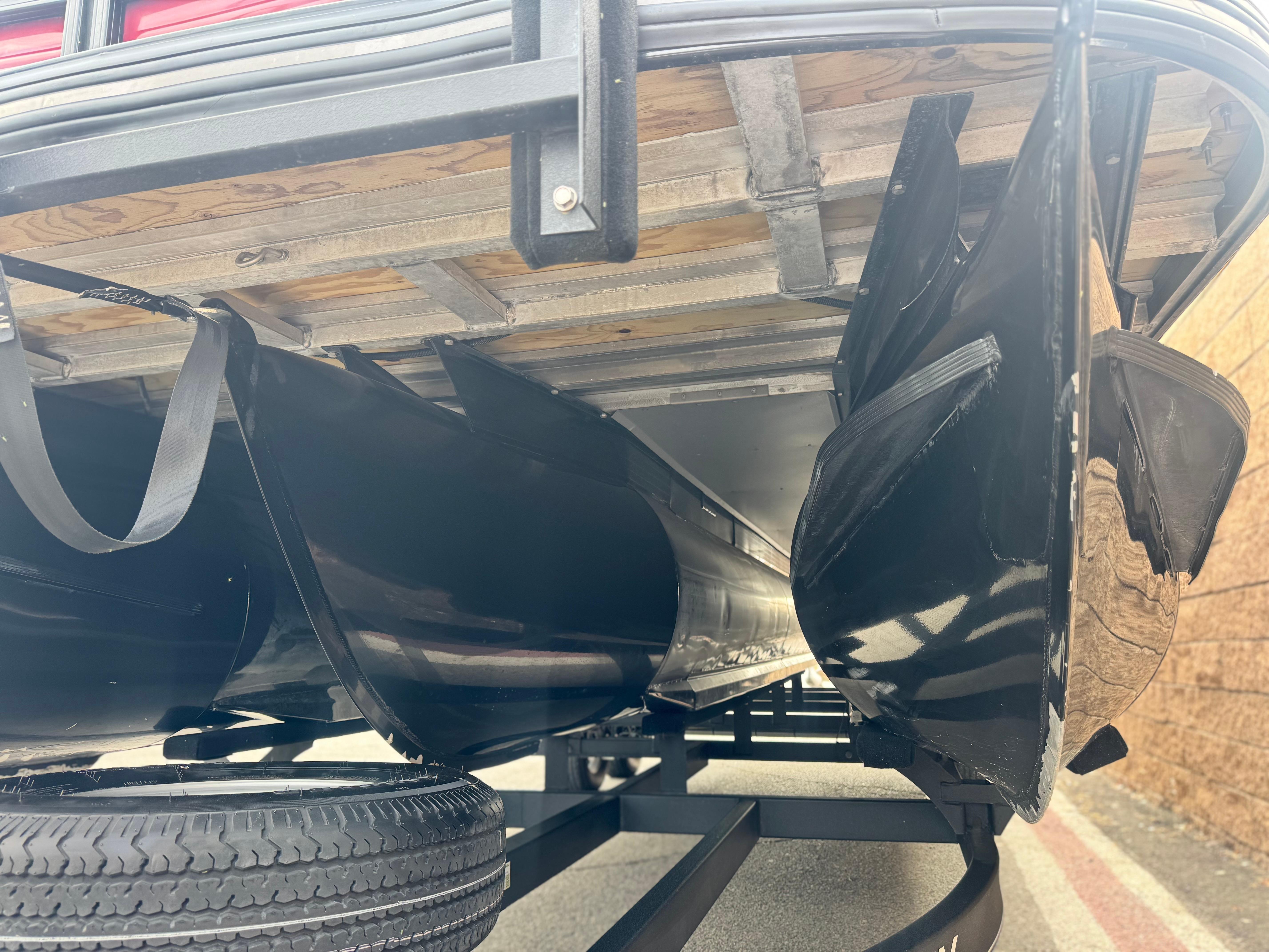 Underside view of 2023 Regency 250 DL3 pontoon boat, showcasing pontoons and trailer.