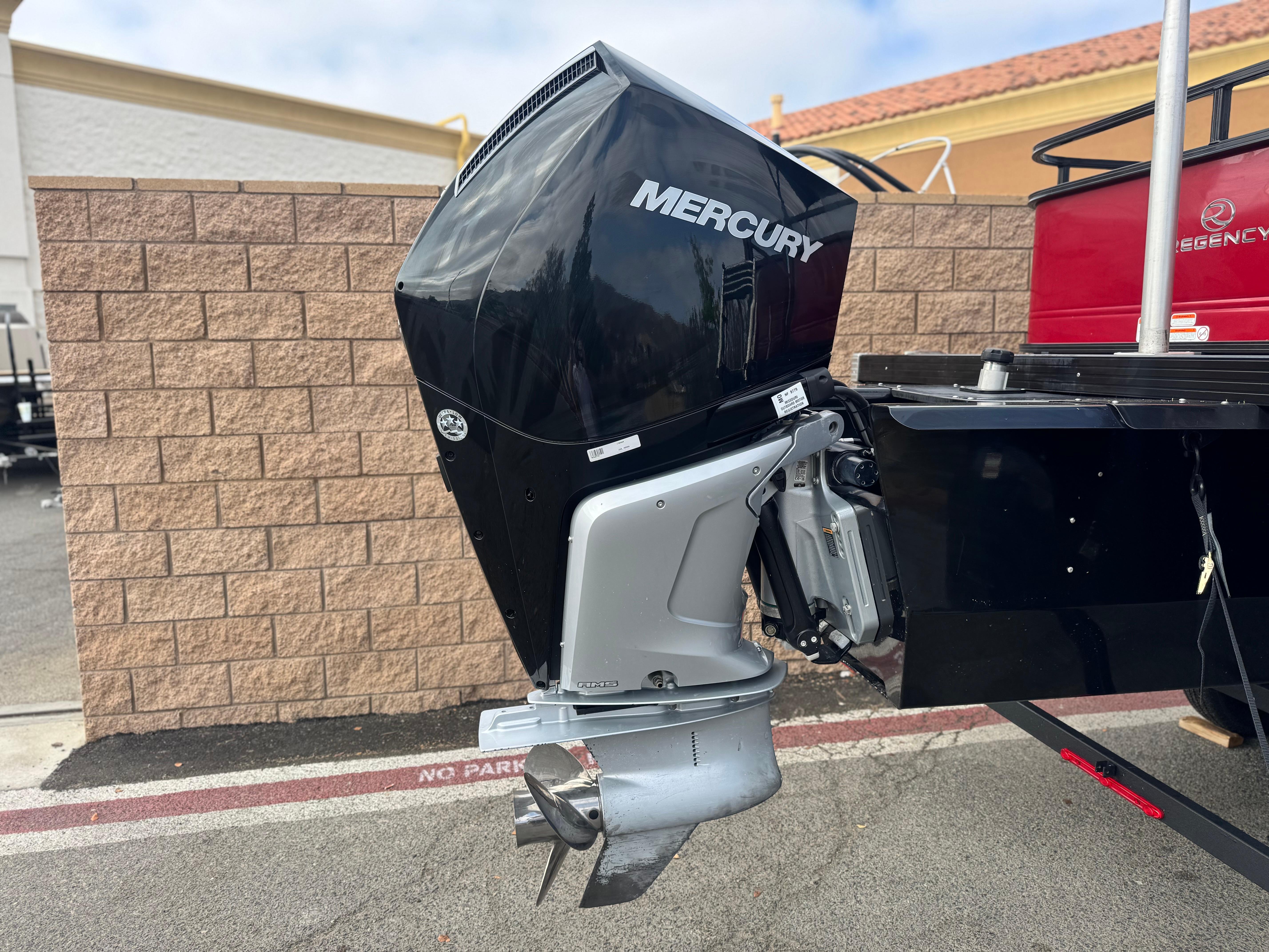 2023 Regency 250 DL3 boat with Mercury outboard motor, parked by a brick wall.