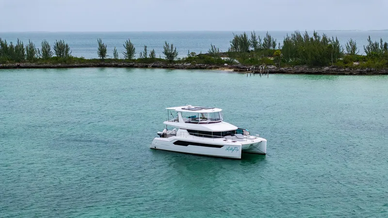 Lollypop Yacht Photos Pics 2022 Leopard 53 Powercat yacht on turquoise water near a lush shoreline.