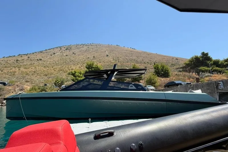  Yacht Photos Pics 2025 Wally Tender 43 yacht docked by a scenic hillside under clear blue skies.