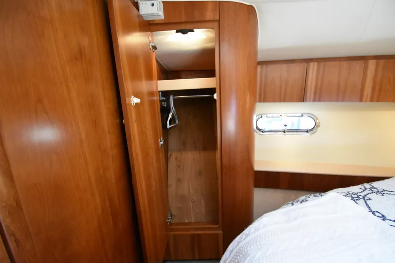 Current Situation Yacht Photos Pics Wooden closet interior on 2001 Tiara Yachts 52 Sport Yacht, featuring hangers and bedding.