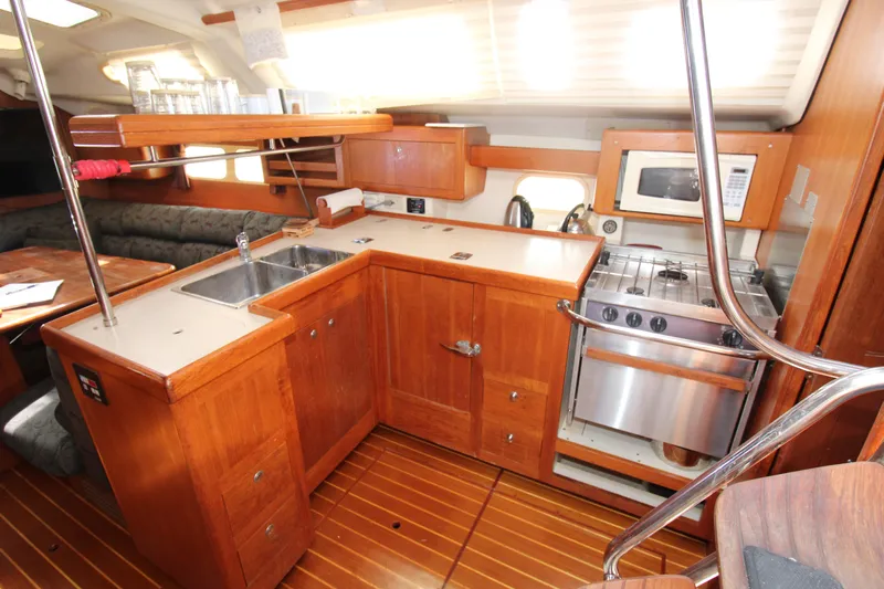Medicinal Yacht Photos Pics 2002 Hunter 410 yacht interior kitchen with wooden cabinetry, stove, and sink.