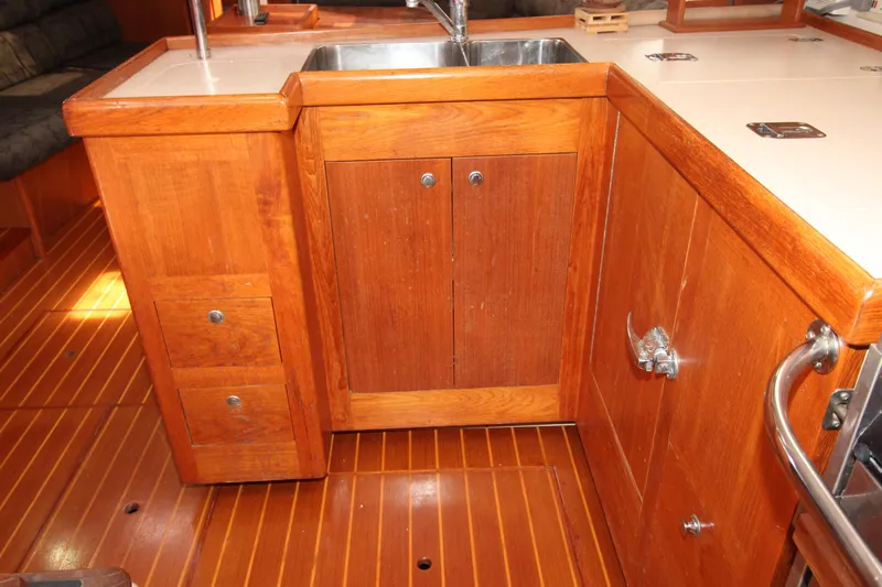 Medicinal Yacht Photos Pics Wooden kitchen area on a 2002 Hunter 410 boat, featuring a sink and storage cabinets.