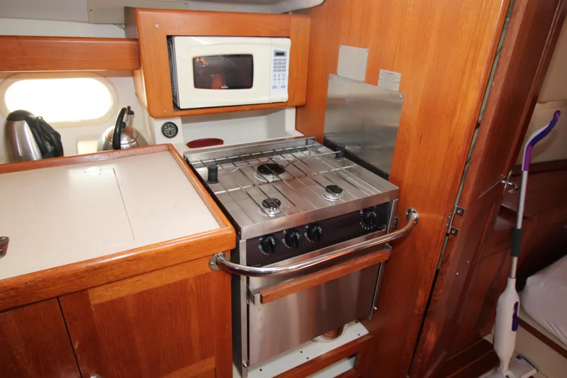 Medicinal Yacht Photos Pics Compact kitchen in 2002 Hunter 410 sailboat with stove, microwave, and wooden cabinetry.