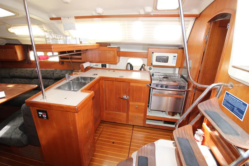 Medicinal Yacht Photos Pics 2002 Hunter 410 yacht interior with wooden cabinetry, kitchen appliances, and seating area.