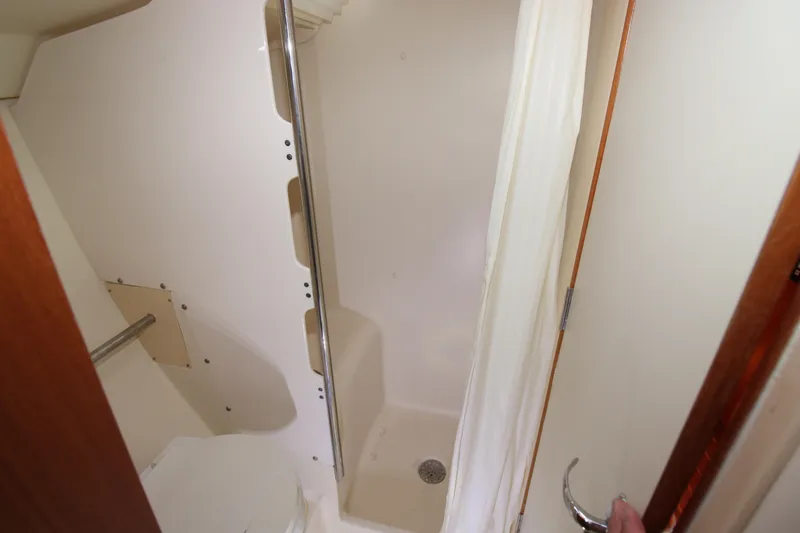Medicinal Yacht Photos Pics Compact shower area in a 2002 Hunter 410 boat, featuring white walls and a curtain.