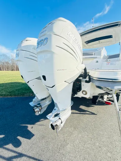 The Good Stuff Yacht Photos Pics 2023 Sea Ray SLX 310 OB with dual outboard engines, parked on pavement.