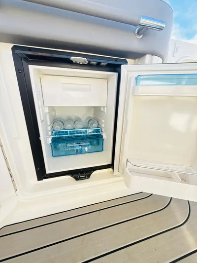 The Good Stuff Yacht Photos Pics 2023 Sea Ray SLX 310 OB boat refrigerator with open door, showcasing interior storage.