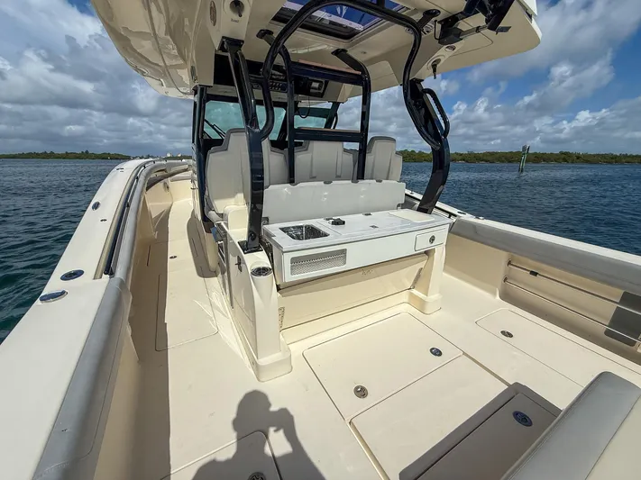  Yacht Photos Pics 2020 Scout 380 LXF boat interior with seating and console, on calm water under cloudy sky.