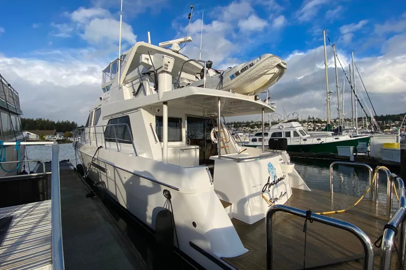  Yacht Photos Pics Luxurious 2001 Compass 57 yacht docked at a marina under a partly cloudy sky.