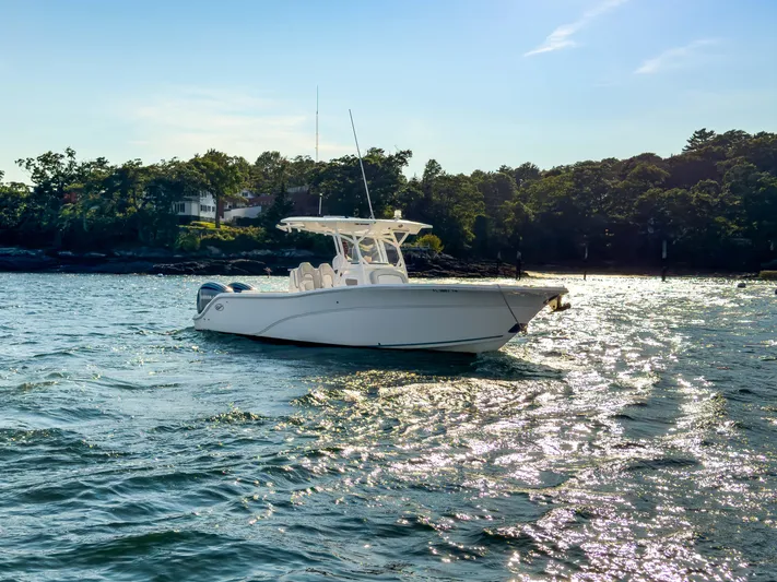 Lil Oa Yacht Photos Pics 2022 Sea Fox 288 Commander boat on shimmering water near a wooded shoreline.