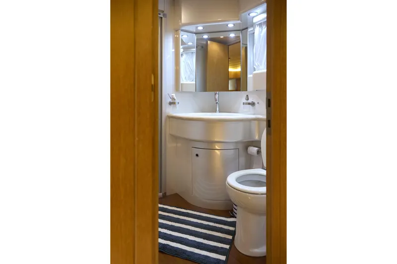  Yacht Photos Pics Luxurious bathroom interior of 2002 Maiora 20 yacht with modern fixtures and striped rug.