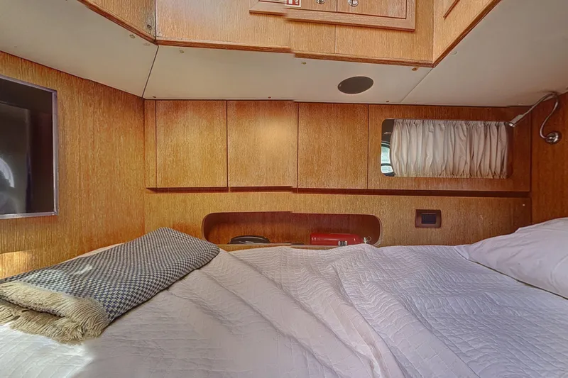  Yacht Photos Pics Cozy cabin interior of 2002 Maiora 20 yacht with wooden paneling and comfortable bedding.